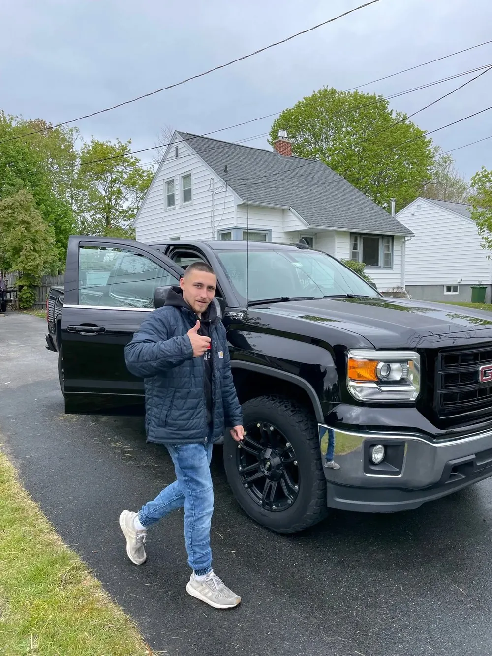 Darkside Detailing owner in front of a detailed black GMC